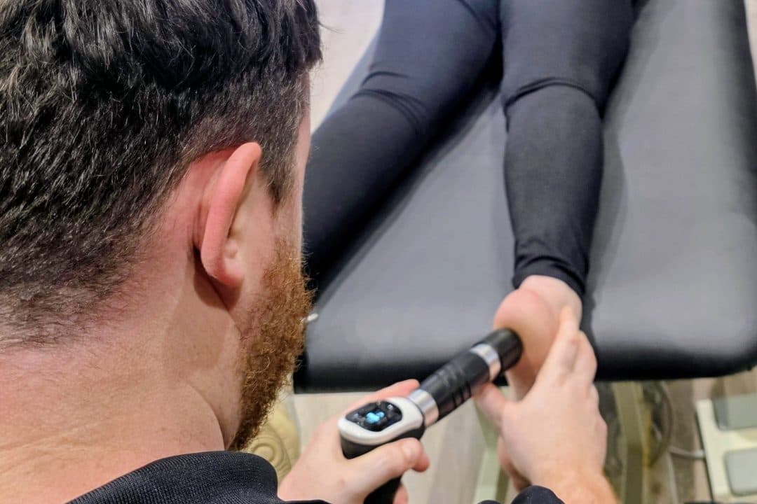 Connor delivering shockwave therapy to a patient&rsquo;s foot at the clinic
